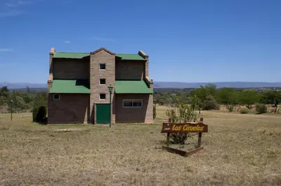 an old house with a sign in the middle of a field at Complejo de cabañas- Lomas del Sol in Los Reartes
