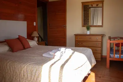 a bedroom with a bed and a dresser and a chair at Complejo de cabañas- Lomas del Sol in Los Reartes