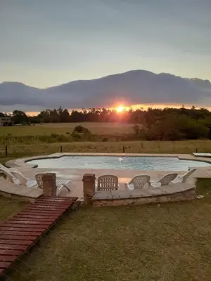 a swimming pool with a sunset in the background at Complejo de cabañas- Lomas del Sol in Los Reartes