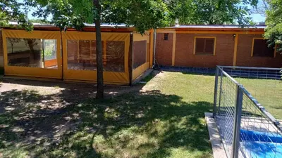 a house with a tree and a tennis court at La Soñada in Villa Quillinzo