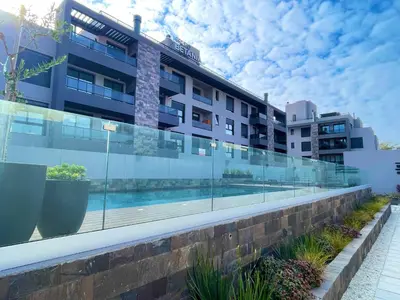 a building with a swimming pool in front of it at Complejo Las Pircas Alta Gracia in Alta Gracia