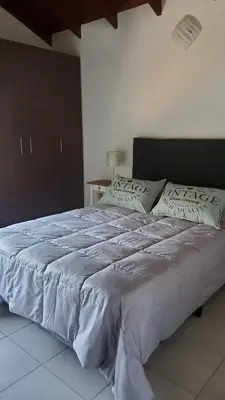 a large bed with white sheets in a bedroom at departamento al pie de las sierras in Villa General Belgrano