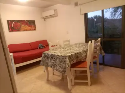 a living room with a table and a red couch at Departamento en Villa Carlos Paz in Villa Carlos Paz