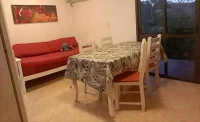 a dining room with a table and a red couch at Departamento en Villa Carlos Paz in Villa Carlos Paz