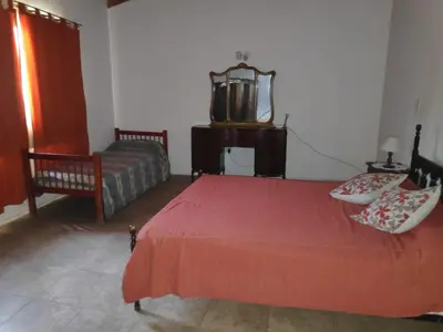 a bedroom with a red bed and a chair at Alquileres centro Mina Clavero in Mina Clavero