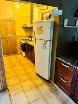 a kitchen with a white refrigerator and wooden cabinets at Casa Tati in Santa Rosa de Calamuchita