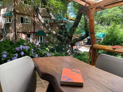 a wooden table with a book on top of it at HOSTEL CASA C Alojamiento, Coworking y Centro Cultural in Villa General Belgrano