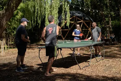 a group of people standing around a ping pong table at HOSTEL CASA C Alojamiento, Coworking y Centro Cultural in Villa General Belgrano