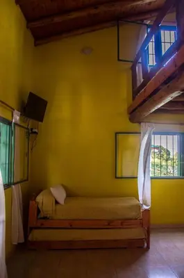 a bedroom with a bed in a yellow wall at Complejo Fra Noi in Villa Anizacate