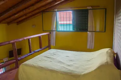 a bed in a room with a yellow wall and a window at Complejo Fra Noi in Villa Anizacate