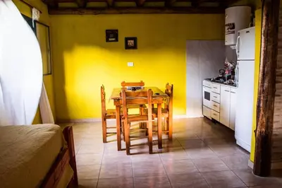a kitchen with a table and chairs and a yellow wall at Complejo Fra Noi in Villa Anizacate