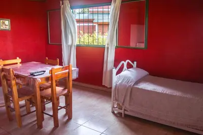 a room with a table and a bed and a table and chairs at Complejo Fra Noi in Villa Anizacate