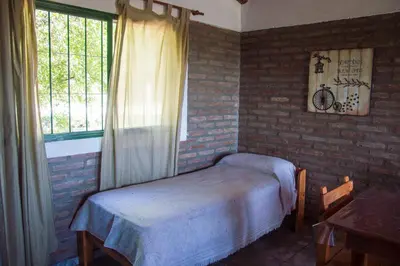 a bedroom with a bed and a brick wall at Complejo Fra Noi in Villa Anizacate