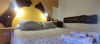 a bedroom with a bed with a wooden headboard at Cabañas La Morada in Nono