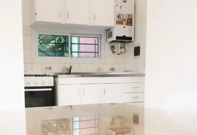 a white kitchen with white cabinets and a window at Quadro Departamentos in Villa Carlos Paz