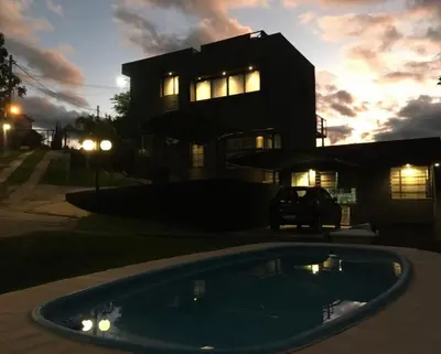 a house with a swimming pool in front of a building at Quadro Departamentos in Villa Carlos Paz