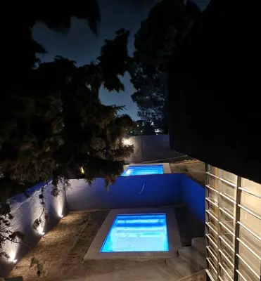 a swimming pool at night with lights on the ground at Quadro Departamentos in Villa Carlos Paz