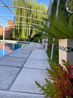 a sidewalk next to a swimming pool with plants at Chalet espectacular in Villa Carlos Paz