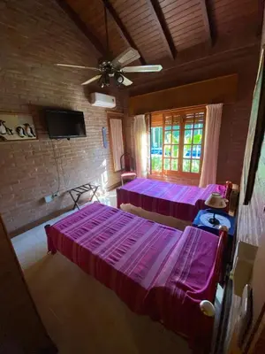 a room with two beds and a ceiling fan at Chalet espectacular in Villa Carlos Paz