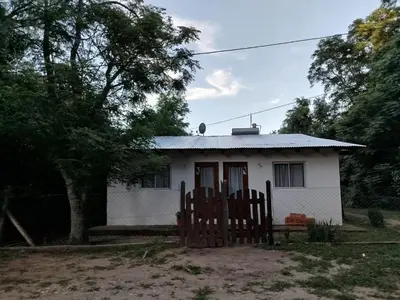 a white house with two chairs in front of it at Cabaña los cuates in Villa Ciudad Parque