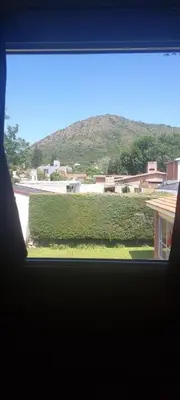 a window with a view of a green hedge at casa balcon del sol in Villa Carlos Paz