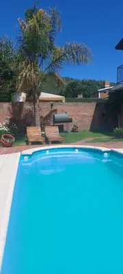 a swimming pool in a yard with a tree and benches at casa balcon del sol in Villa Carlos Paz