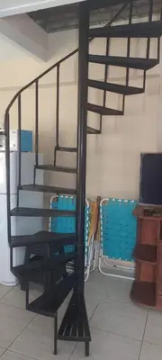 a black spiral staircase in a room with blue chairs at casa balcon del sol in Villa Carlos Paz