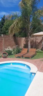 a swimming pool with two benches and a palm tree at casa balcon del sol in Villa Carlos Paz