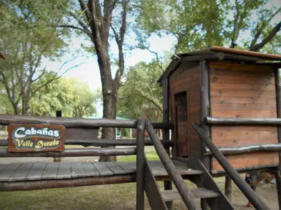a wooden cabin with a sign on a fence at Cabañas Valle Dorado in Villa Rumipal