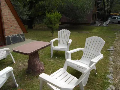 three white chairs and a table in a yard at Cabañas Valle Dorado in Villa Rumipal