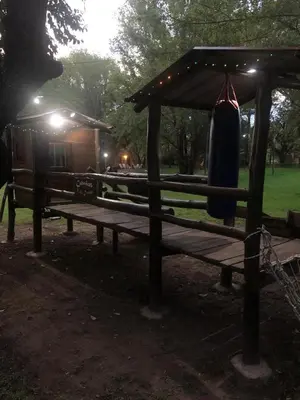 a wooden bench with a gazebo and a house at Cabañas Valle Dorado in Villa Rumipal