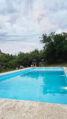 two chairs sitting next to a blue swimming pool at Complejo MASVISTA in San Antonio de Arredondo