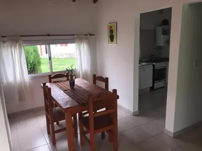 a kitchen with a wooden table and chairs and a kitchen with a window at Cabañas Luciano in Arroyo de Los Patos