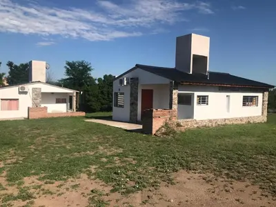 a white house with two chimneys on top of a yard at Cabañas Luciano in Arroyo de Los Patos