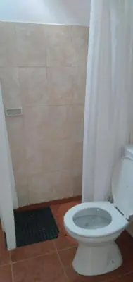 a bathroom with a white toilet and a shower at La Colonial Cabañas in Villa Cura Brochero