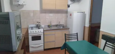 a kitchen with a stove and a sink and a refrigerator at La Colonial Cabañas in Villa Cura Brochero