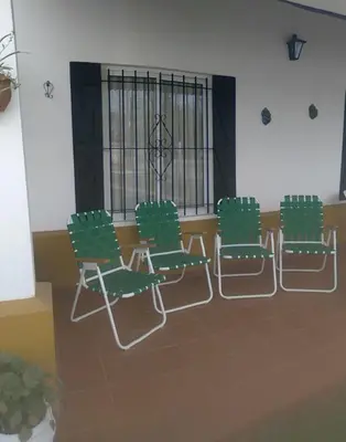 four green chairs in a room with a window at La Colonial Cabañas in Villa Cura Brochero