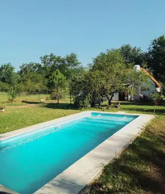 a blue swimming pool in a yard with a house at Casa VD in Santa Rosa de Calamuchita