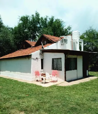 a small white house with red chairs and a table at Casa VD in Santa Rosa de Calamuchita