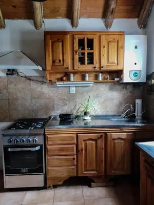 a kitchen with wooden cabinets and a stove top oven at Casa VD in Santa Rosa de Calamuchita
