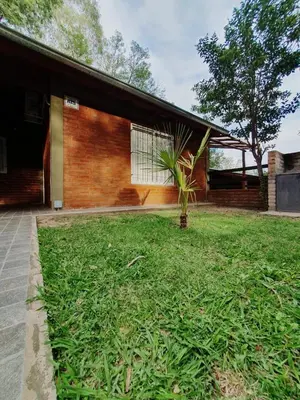 a house with a grassy yard in front of a building at Cabañas del Puente - Rio Grande San Luis in La Bajada