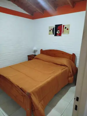 a bedroom with a wooden bed with orange sheets at Cabañas del Puente - Rio Grande San Luis in La Bajada
