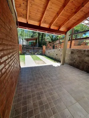 an outdoor patio with a wooden roof and a brick wall at Cabañas del Puente - Rio Grande San Luis in La Bajada
