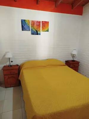 a bedroom with a yellow bed and two pictures on the wall at Cabañas del Puente - Rio Grande San Luis in La Bajada