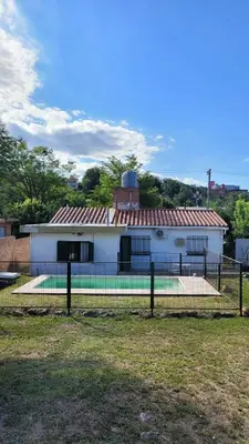 a white building with a fence in front of it at Casa Cedro Azul II in Villa Carlos Paz