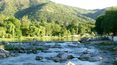 a river with rocks and mountains in the background at Monarcas III in Villa Carlos Paz