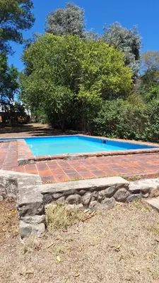 a swimming pool in a yard with a stone wall at CASA EN VILLA LA BOLSA, Córdoba in Cordoba