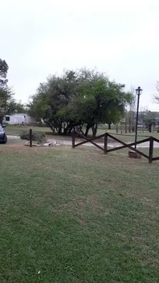 a wooden fence in a field with a tree at Estancia la aguada in Embalse