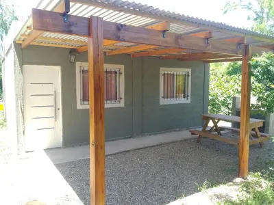 a pergola with a picnic table and a bench at Cabaña Calamuchita Rumipal in Villa Rumipal