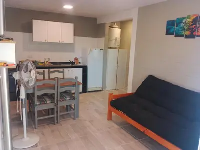 a kitchen and a living room with a couch at Cabaña Calamuchita Rumipal in Villa Rumipal